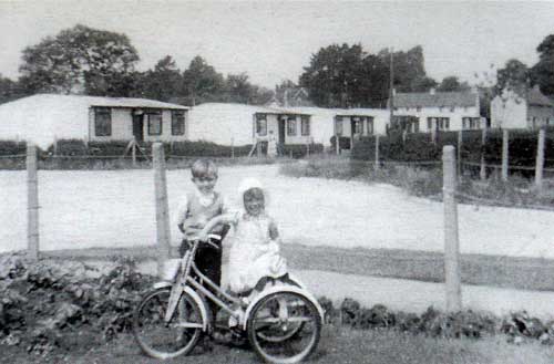 This picture shows the prefabs in what is now Greenvale Drive with St John's Road running off to the right. The children are Brian and Jennifer Robinson in 1955